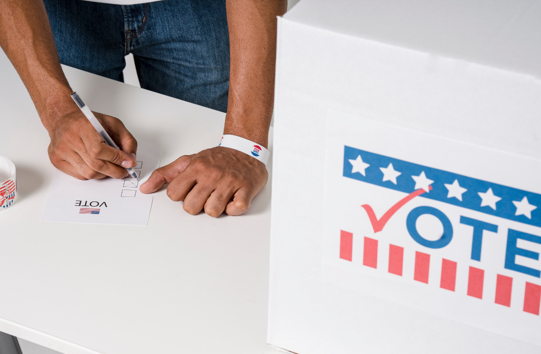 image of a voter filling out a ballot next to a ballot box